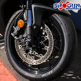 Black front axle sliders by SHOGUN, mounted on a motorcycle body for protection and style.