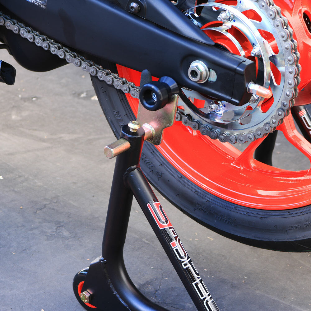 Black SHOGUN swingarm sliders for motorcycle body protection, shown mounted on a bike's swingarm.