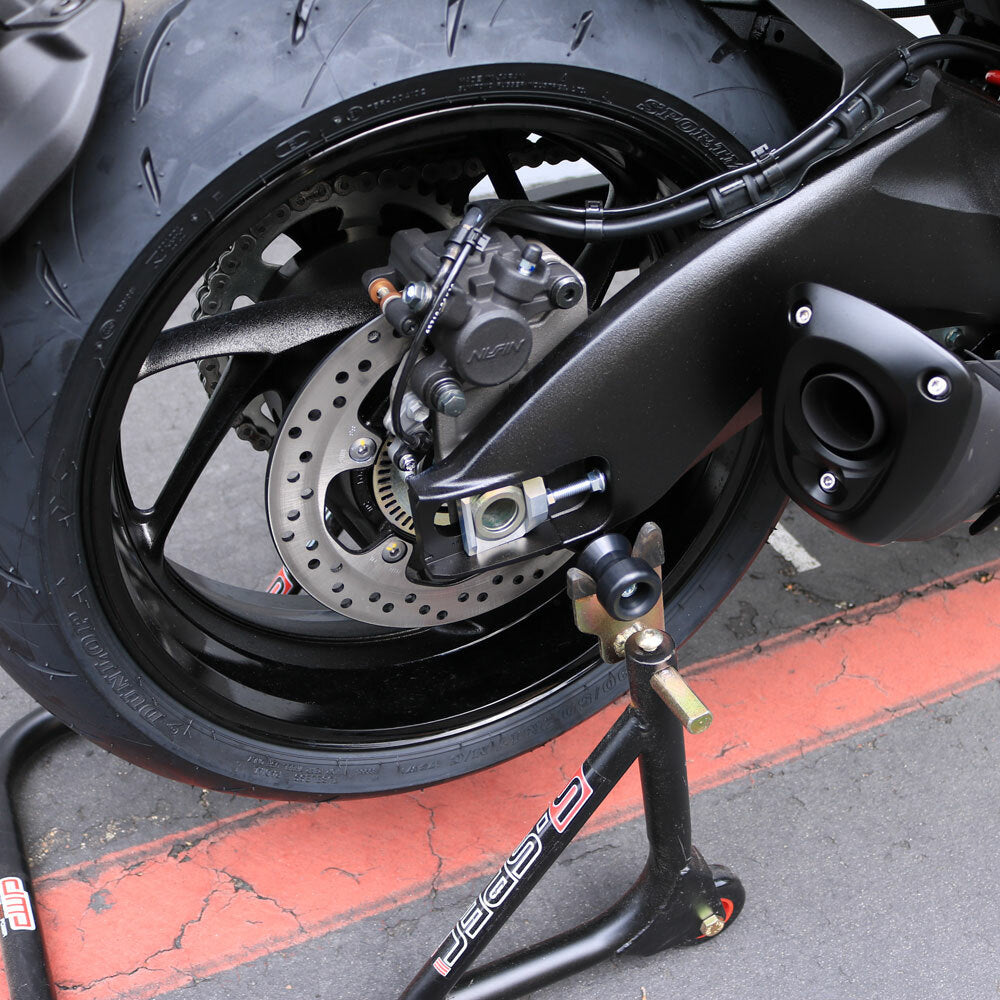 Black Shogun swingarm sliders for motorcycle body protection, shown mounted on a bike's swingarm.