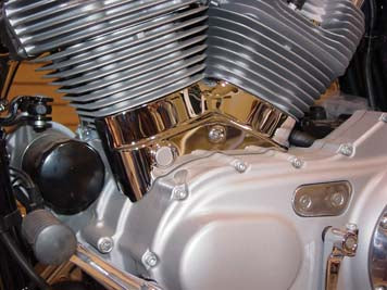 V-Twin chrome left side engine cylinder base cover for motorcycle engine with polished finish and detailed design.