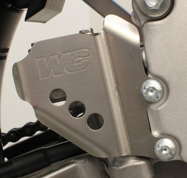 WORKS rear master cylinder guard for RMZ250 motorcycle, protective metal brace with black finish and mounting hardware.
